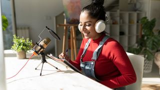 A young woman works on her side hustle podcast from home.