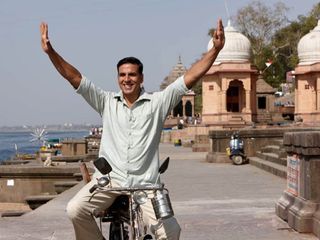 Akshay Kumar on a bicycle smiing in pad man