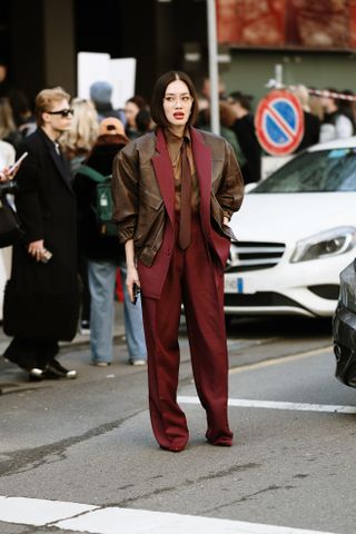 a guest at Milan Fashion Week wears a burgundy suit with slouchy pants