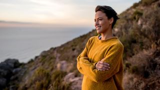 Woman looking out across a view with arms crossed in the fresh air