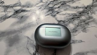 Ett laddningsfodral till Huawei FreeBuds Pro 3 ligger på ett ljust, marmormönstrat bord.