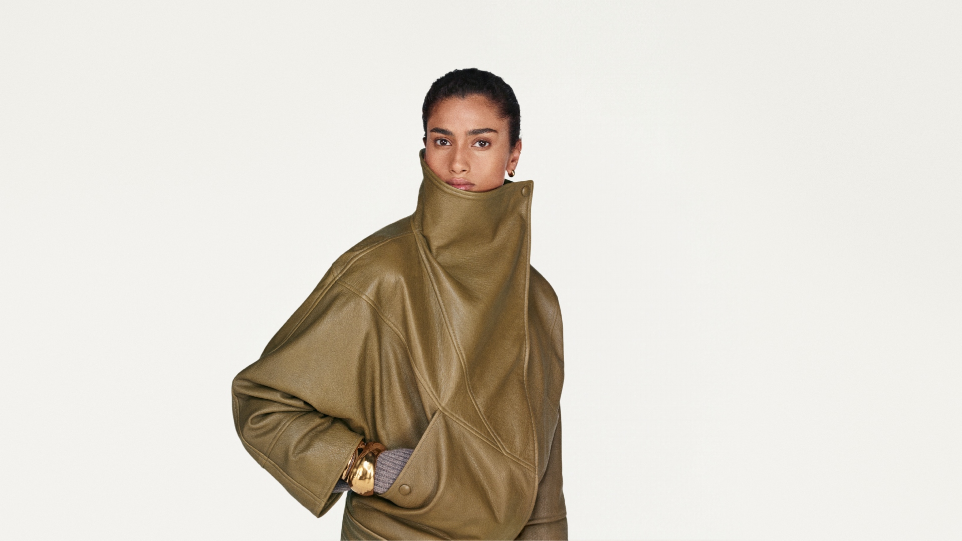 A model wearing a brown high-neck leather jacket.