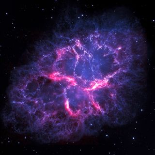 A composite image of the Crab Nebula. In blue are visible light observations from the Hubble Space Telescope, showing gas emissions caused by energy from a neutron star at the center of the nebula. In red are infrared observations from the Herschel Space Observatory, revealing cold dust and gas.