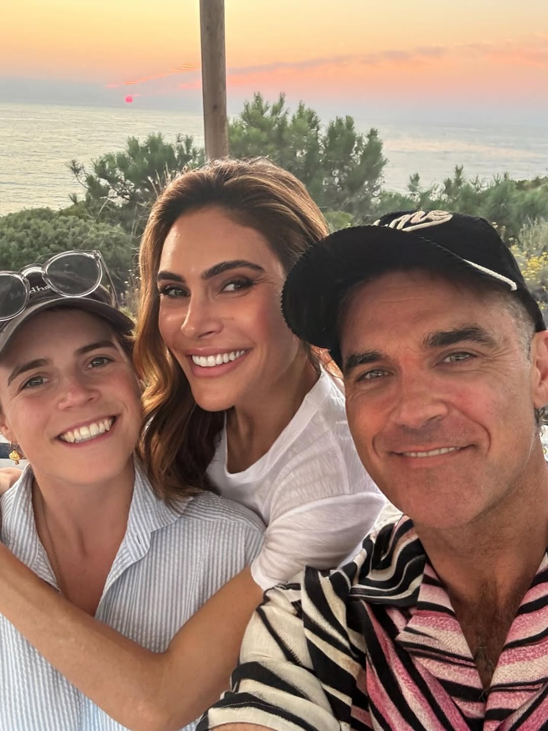 Princess Eugenie, Ayda Field Williams and Robbie Williams taking a selfie and smiling with the sea in the background
