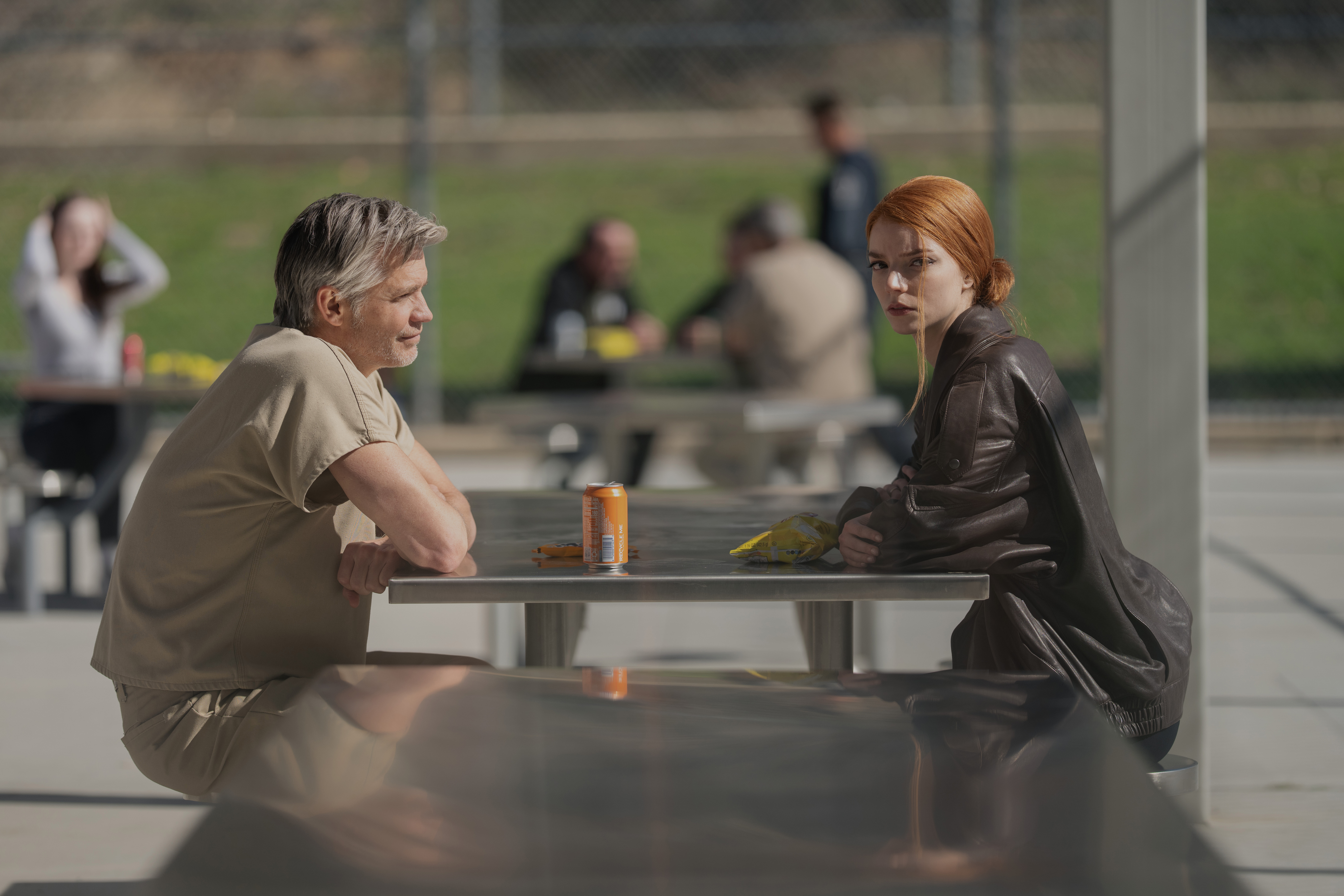timothy olyphant as john talking to anya taylor joy as his daughter lucky across a table in a prison yard in the tv show lucky