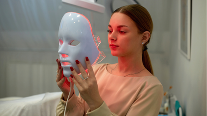 Beautiful young woman getting a led light therapy mask treatment for her face - stock photo