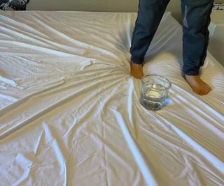 A child standing beside a glass of water on the Leesa Original Mattress.