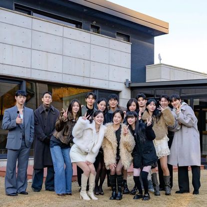 The 'Single's Inferno Reunion' cast poses for a group picture, standing outdoors on the front lawn of a modern home.
