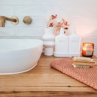 Styled vanity candle detail with candle, earthy hand towel, and white accessories