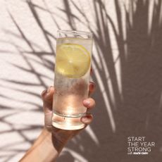 A woman holding a glass of lemon water