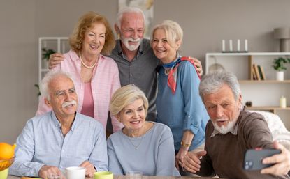 A group of happy seniors smile for a selfie, displaying joy, connection, and the beauty of companionship in a warm, inviting atmosphere.
