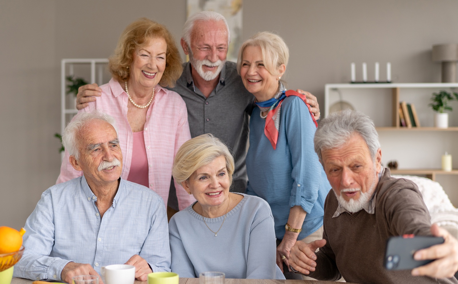 A group of happy seniors smile for a selfie, displaying joy, connection, and the beauty of companionship in a warm, inviting atmosphere.