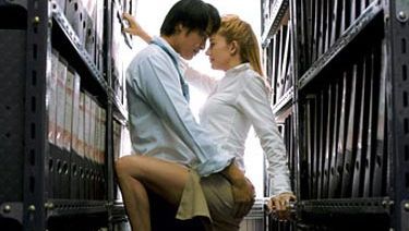 man and woman making out between shelves of files
