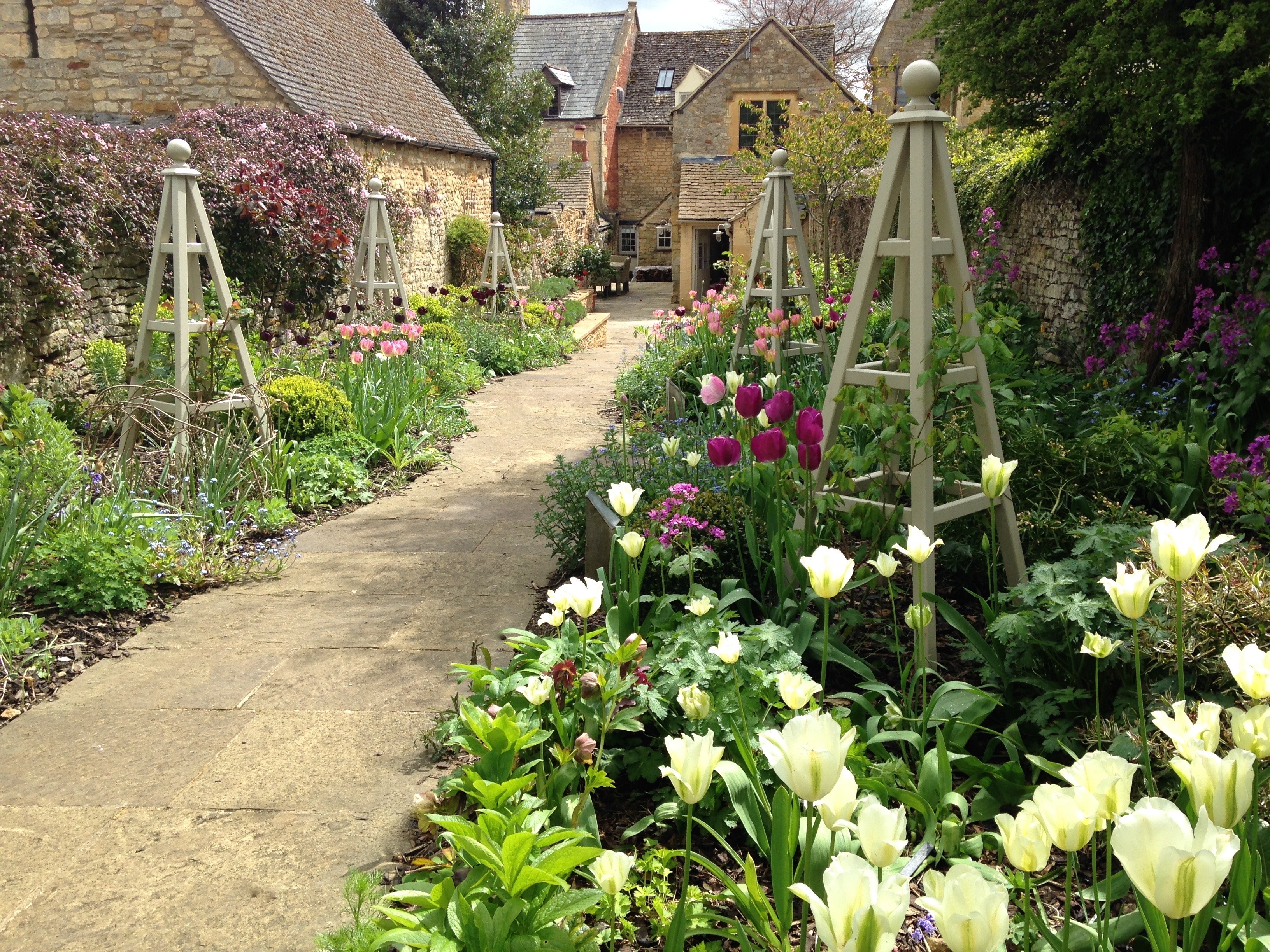 series of wooden obelisks in flowerbeds alongside a pathway