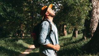 Man breathing deeply while hiking in forest