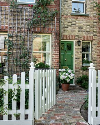 path beyond a sage green fence, winding through the front garden of a victorian home to the door