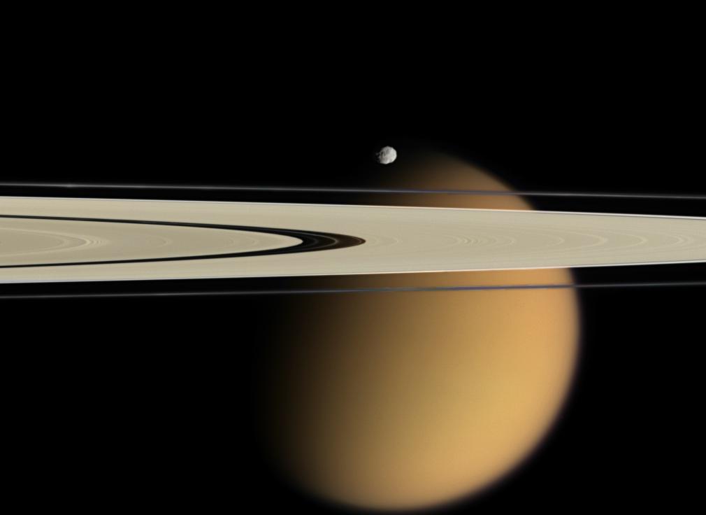 The blurring effects of Titan&#039;s aerosol are obvious in this image, where the orange moon peeks from behind two of Saturn&#039;s rings. Small, battered Epimetheus, another of Saturn&#039;s 62 moons, appears just above the rings. 