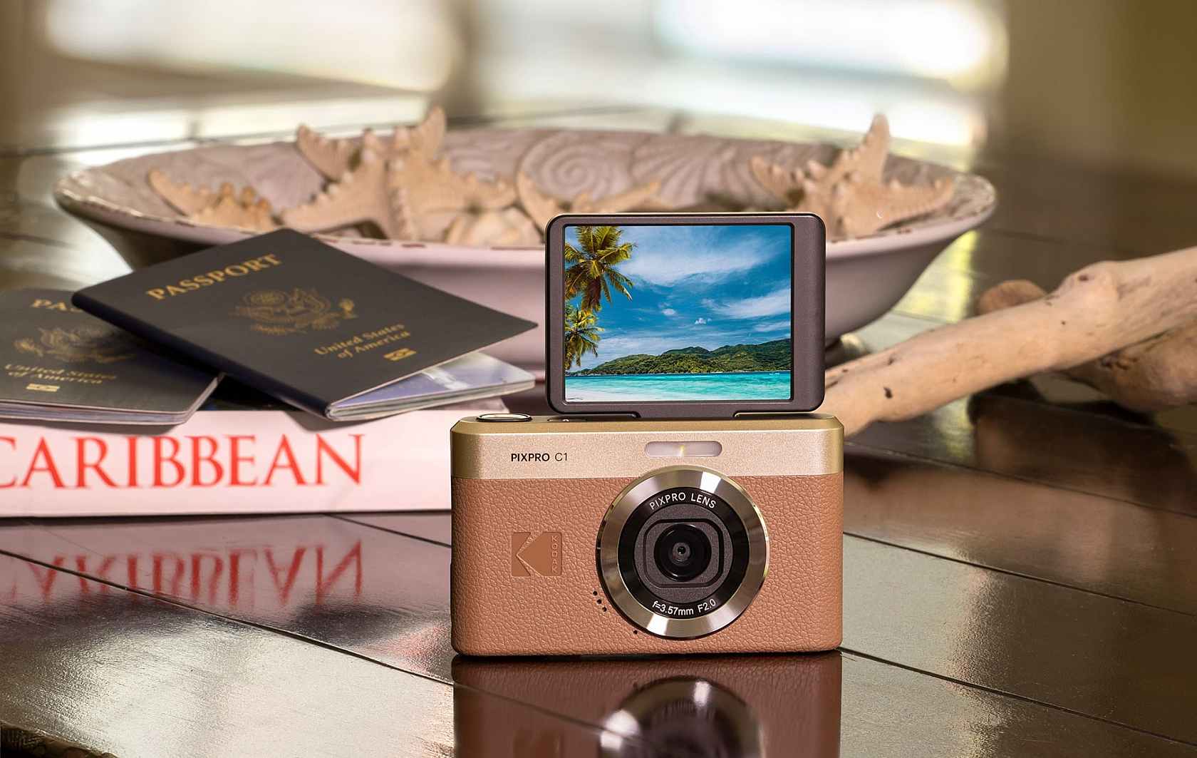 Kodak Pixpro C1 on a table in front of passports, a holiday book and a bowl of shells