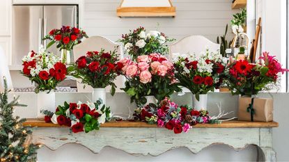 Many flower bouquets with white, red, and pink flowers, displayed on a table with a gift package.