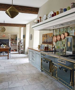 Stone kitchen flooring ideas in a large open plan space with dark blue vintage range oven.