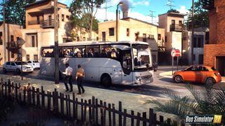 A promotional render for Bus Simulator 27 that shows a white bus parked at the side of the road in a fictional southern European town. 