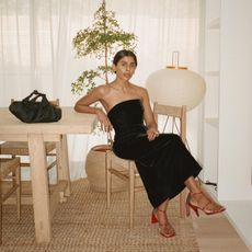 Fashion influencer Monikh Dale wearing a black strapless dress and red heels in her London home.