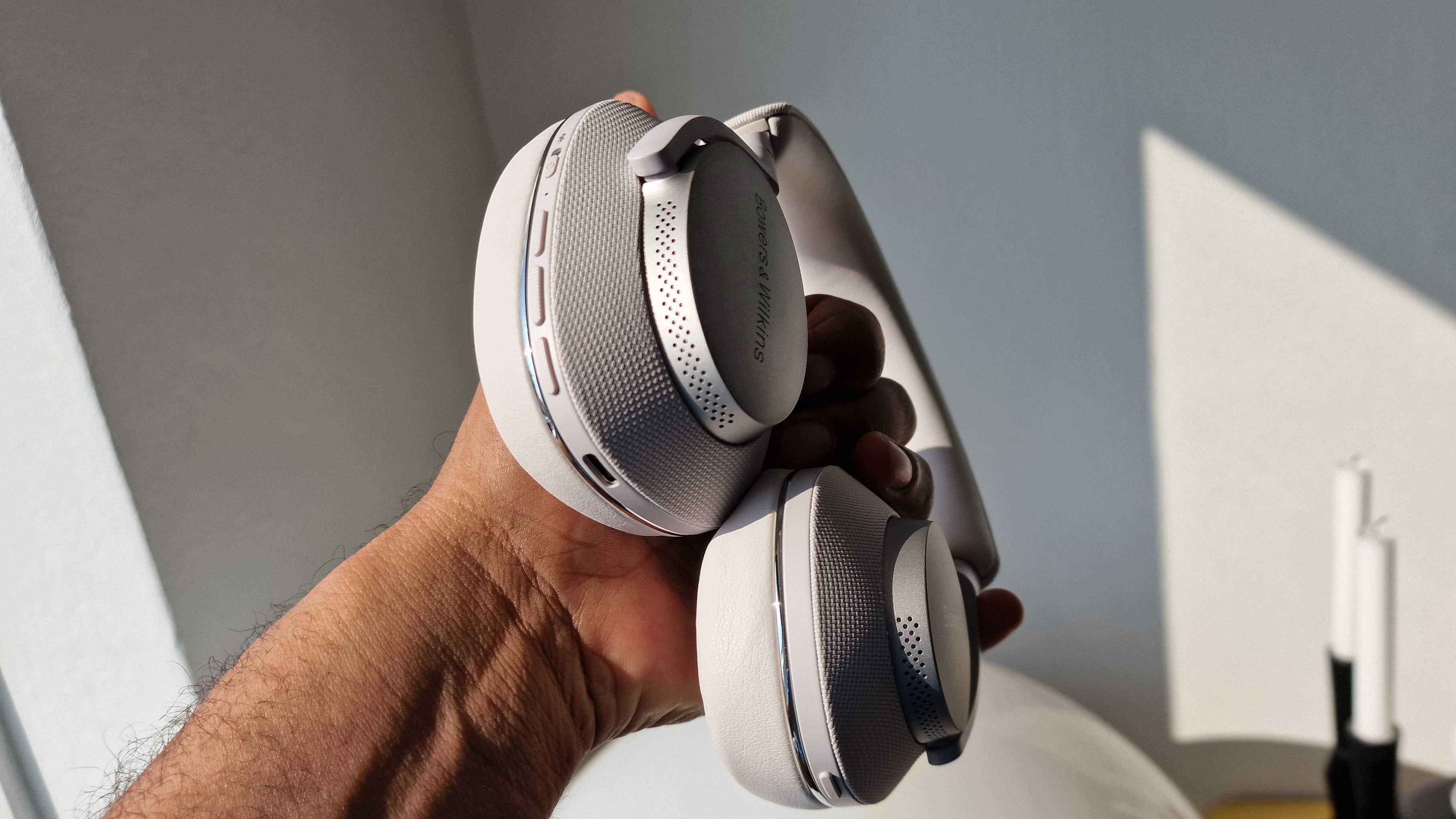 Bowers & Wilkins PX7 S2 holdt i hånden i sollys indenfor
