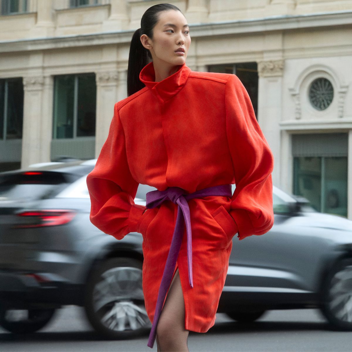 a model posing in paris wearing a red coat