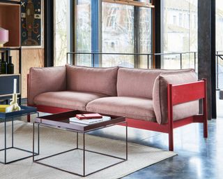 A wooden framed sofa with red finish and red Kvadrat upholstery in a mid-Century style interior