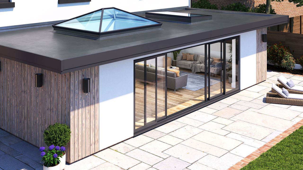 Contemporary extension featuring multiple Korniche bi-fold doors, roof lantern and flat galls roof window in front of stone patio