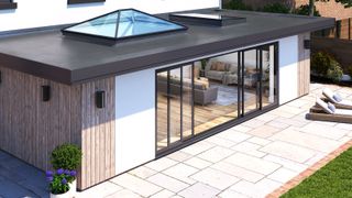 Contemporary extension featuring multiple Korniche bi-fold doors, roof lantern and flat galls roof window in front of stone patio