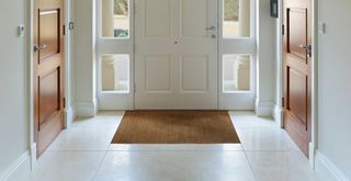 front door from inside a hallway with tiled floor to support a guide for how to clean tile floors