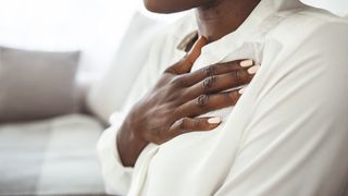 Woman in white shirt holds her hand over her heart