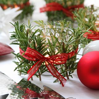 red ribbon bow around rosemary sprigs and tea light holder