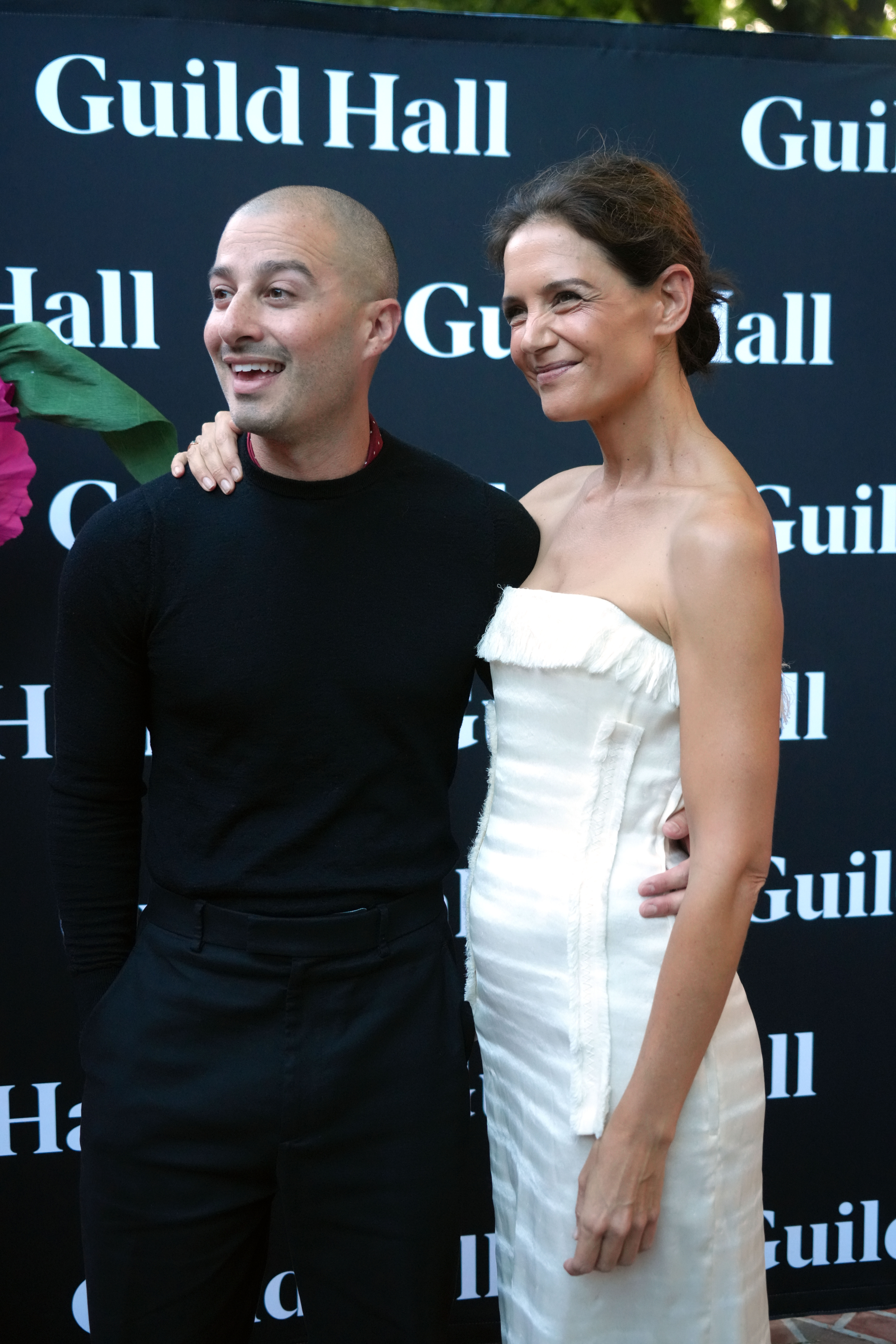 Katie Holmes wears a strapless white dress and carries a soft leather bag while posing with boyfriend Jason Bard Yarmosky at the 2026 Guild Hall Summer Gala on August 7, 2026
