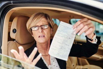 Businesswoman looking upset at receiving a traffic ticket.