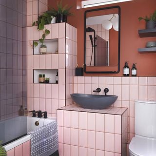 pink tiled bathroom with blue freestanding sink and black taps