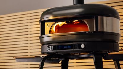Black domed pizza oven with two serving boards and a digital display