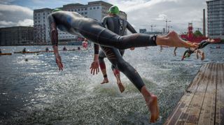 Two swimmers dive into the Royal Victoria Dock as part of the London Triathlon