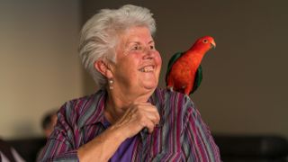 Bird sitting on shoulder of senior woman