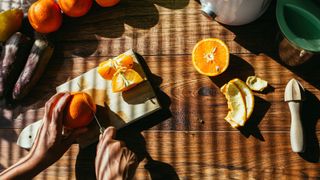 Woman's hands cutting up oranges on a chopping board in sunlight