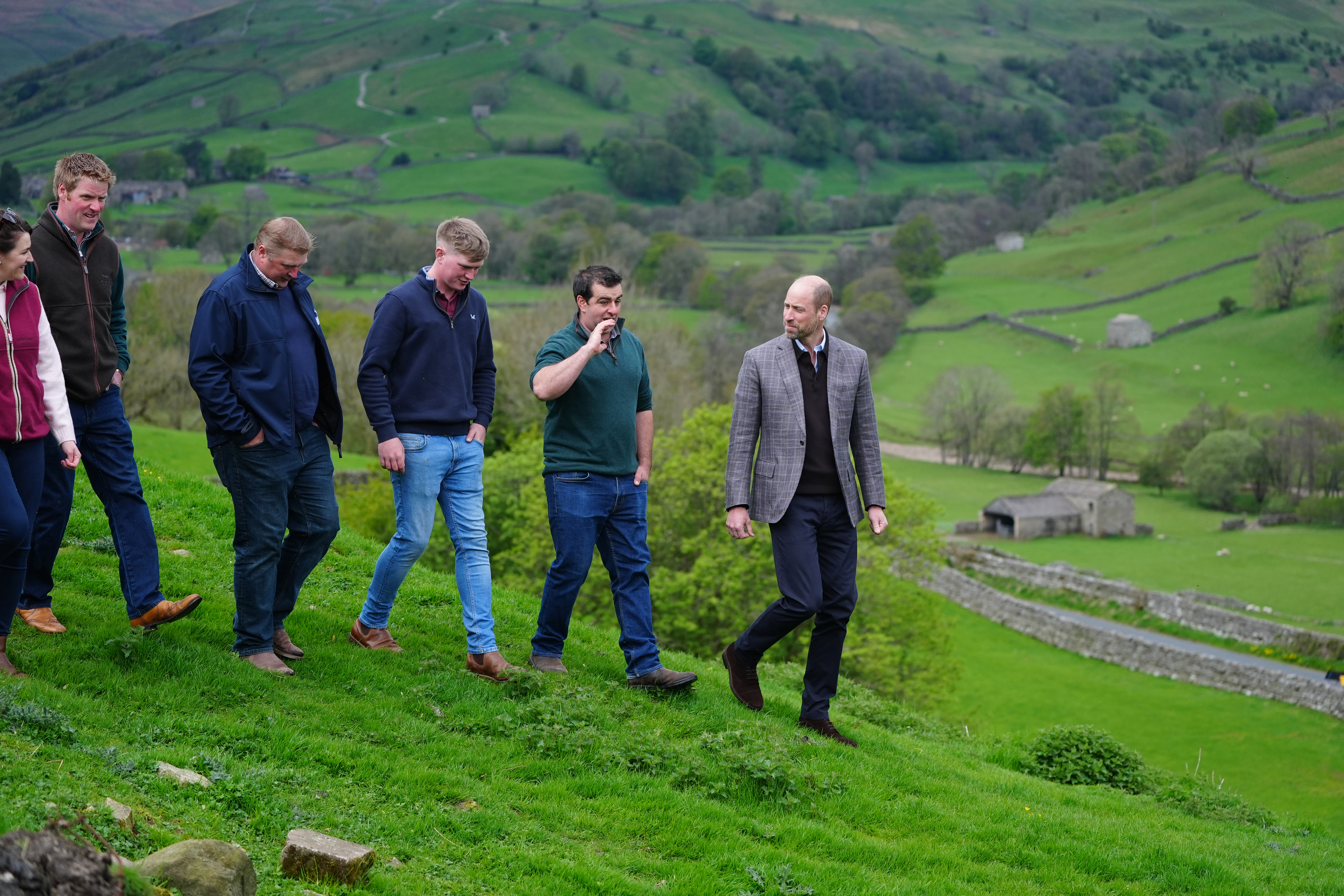 Prince William walking on a hill with farmers