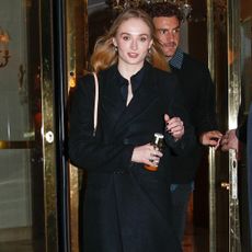 Sophie Turner wearing a black coat