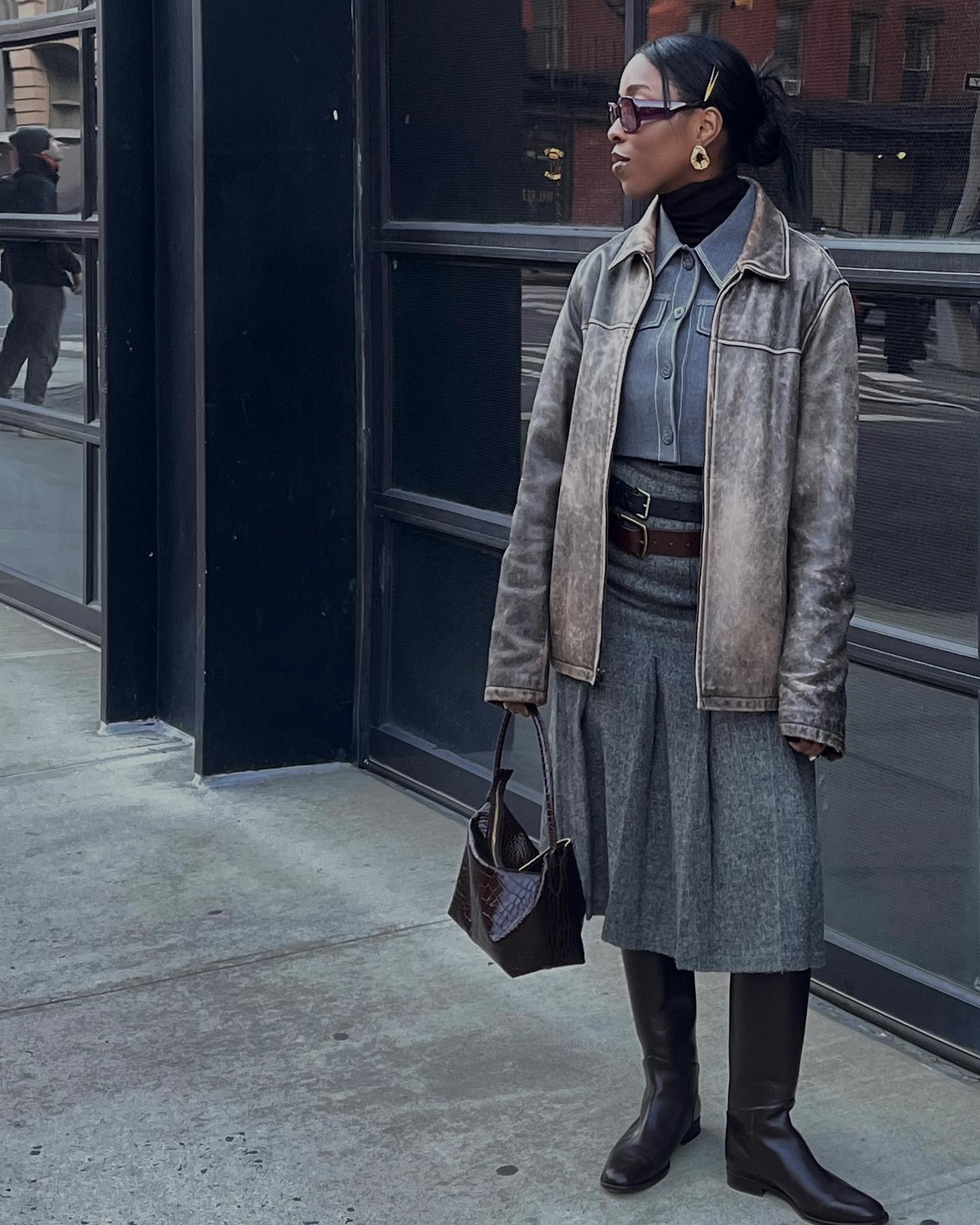 @cortnebonilla wears a grey pleated skirt and leather jacket