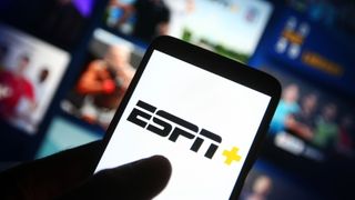 ESPN+ (ESPN Plus) logo of an US video streaming service is seen on a smartphone with its website in the background.