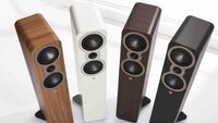 Four Q Acoustics 3040c floorstanding speakers in different finishes arranged in a curved formation.
