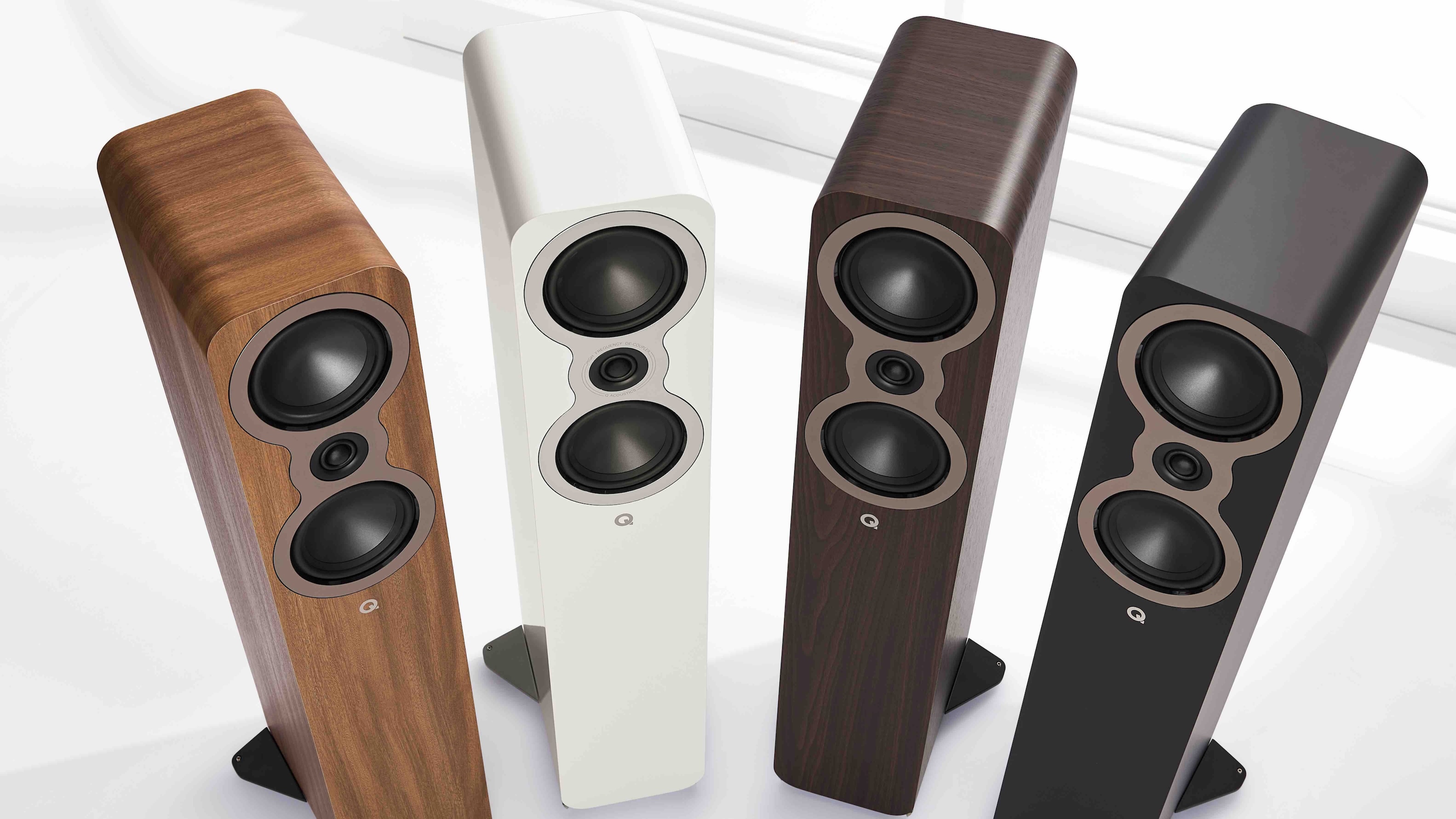 Four Q Acoustics 3040c floorstanding speakers in different finishes arranged in a curved formation.