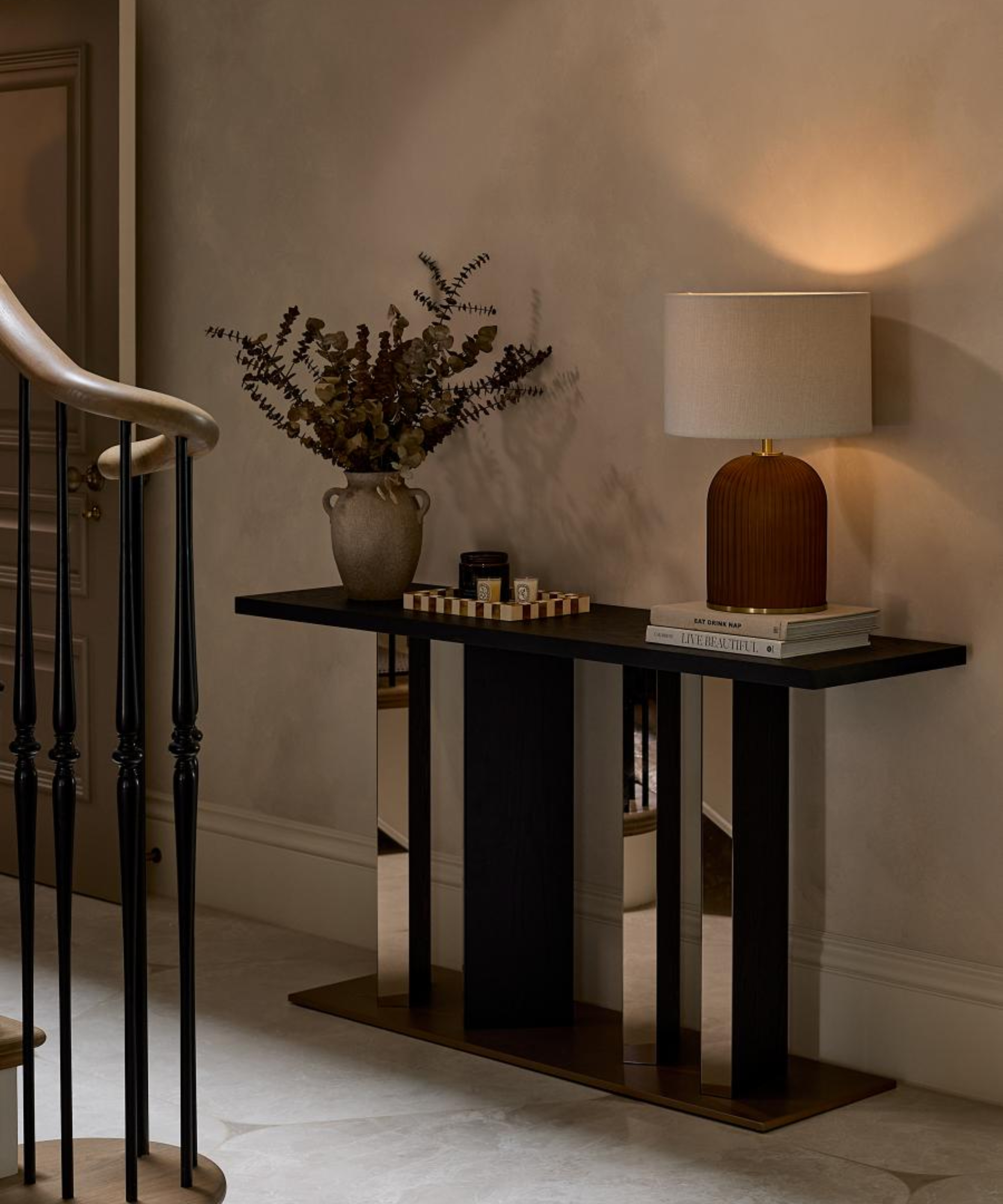 hallway with black and mirrored gold small console table with decorative items and lamp