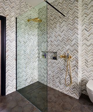 Shower illustrated by grey herringbone tiles and gold accents.