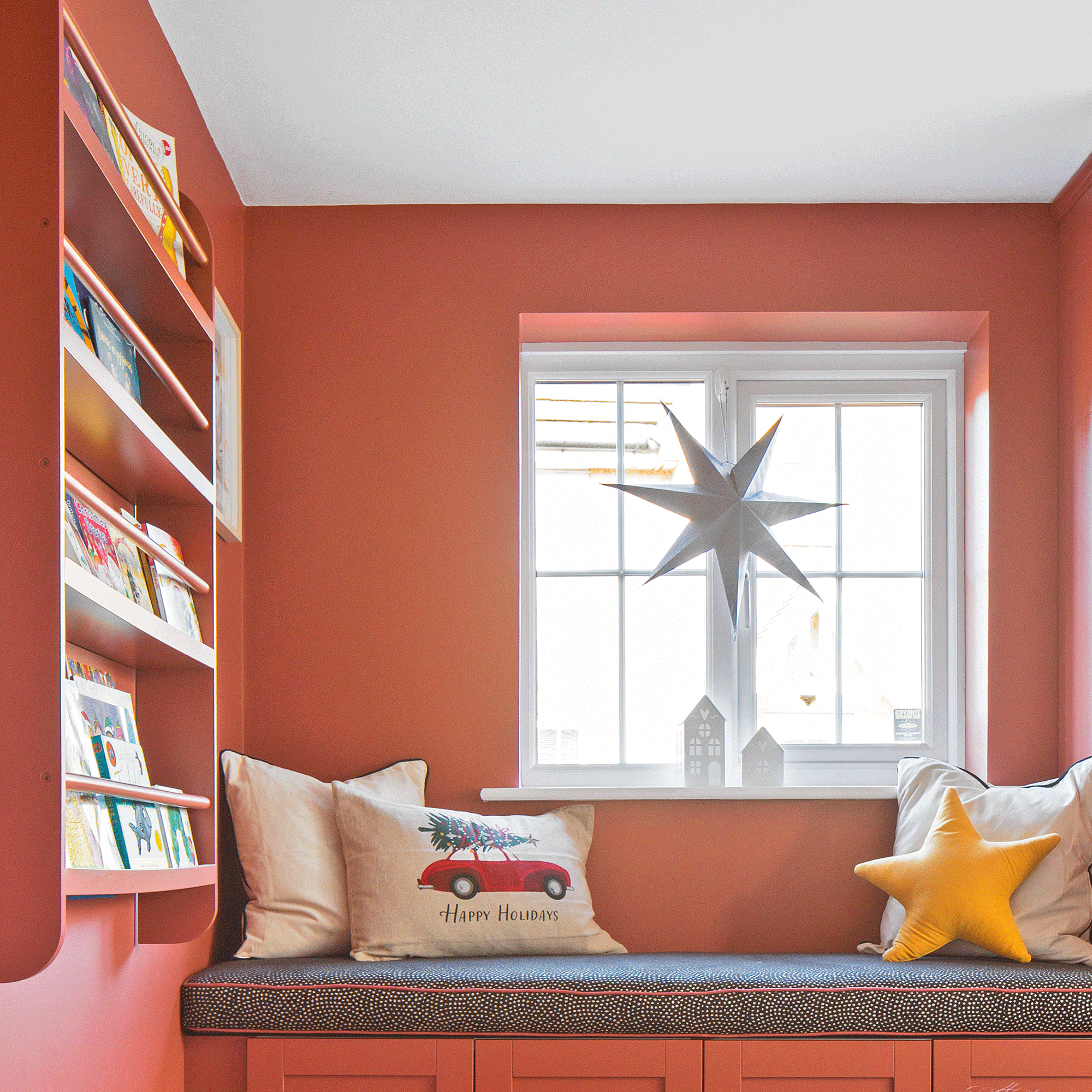 a red painted playroom with window seat and wall-hung bookshelf